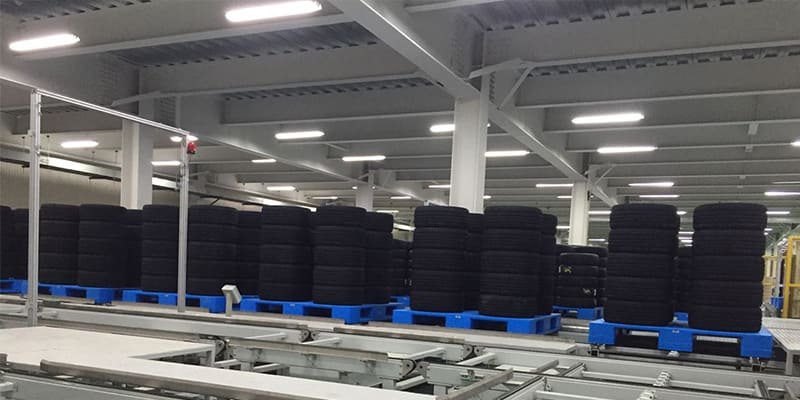 Heavy - duty industrial plastic pallets neatly stacked in a large warehouse for heavy - load storage.