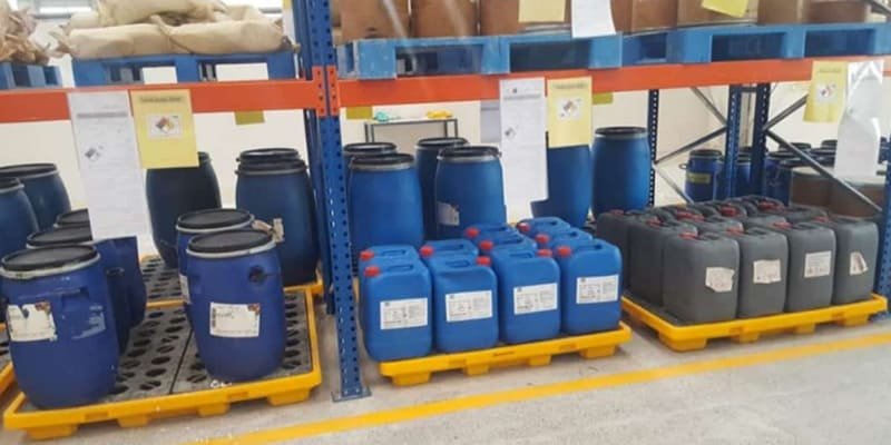 Heavy - duty industrial plastic pallets in blue and grey supporting large drums in industrial material storage.