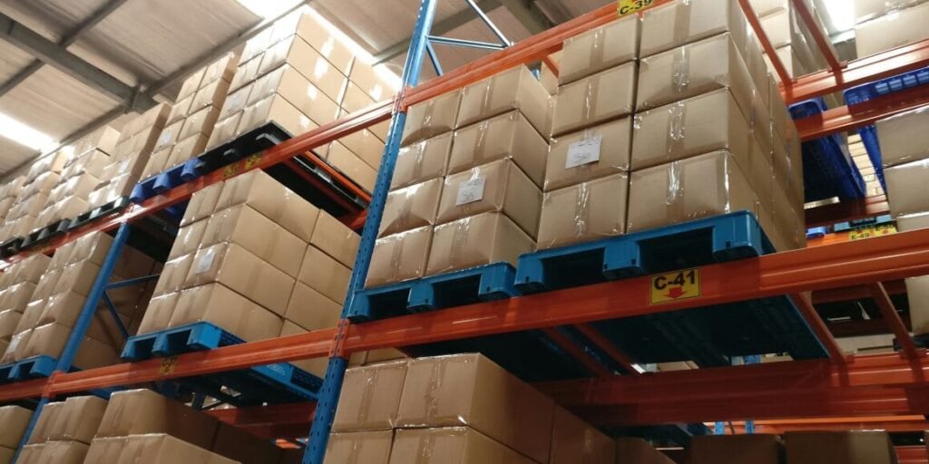 Industrial plastic pallets supporting cardboard boxes on racks in a warehouse, demonstrating storage functionality.
