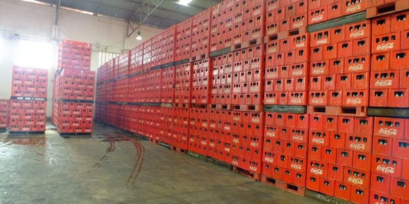 Stackable plastic pallets in red, highly stacked in a warehouse for large - scale storage.