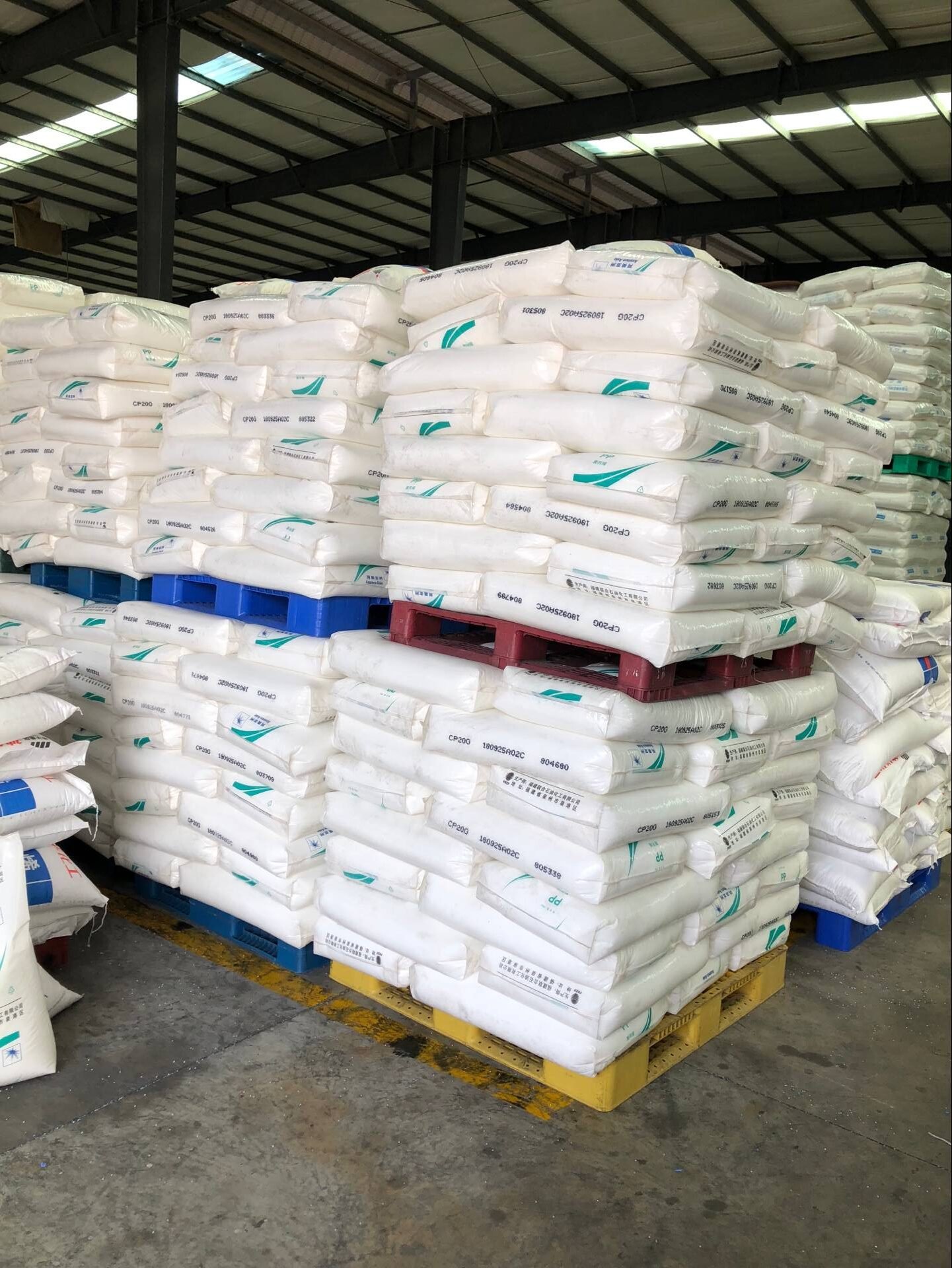 Stacked bagged materials on reusable plastic pallets in a warehouse